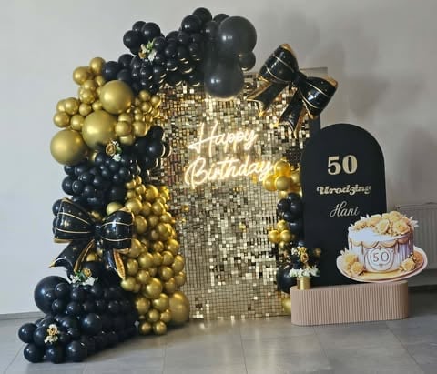 Elegant 50th birthday party display with gold and black balloons, sequin backdrop, black arch sign, and cake decoration.