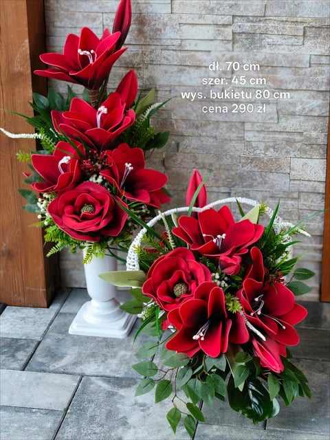 Two vibrant red flower arrangements in white vases with green foliage against a stone tile wall