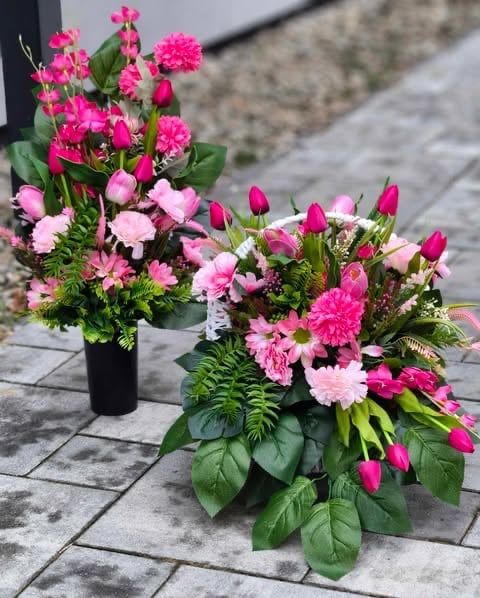 Two floral arrangements with pink and magenta carnations and dahlias in vases on a paved surface